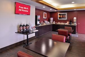 Habitación de hotel con zona de comedor, estación de café y un cartel que indica acceso a Wi-Fi gratuito.