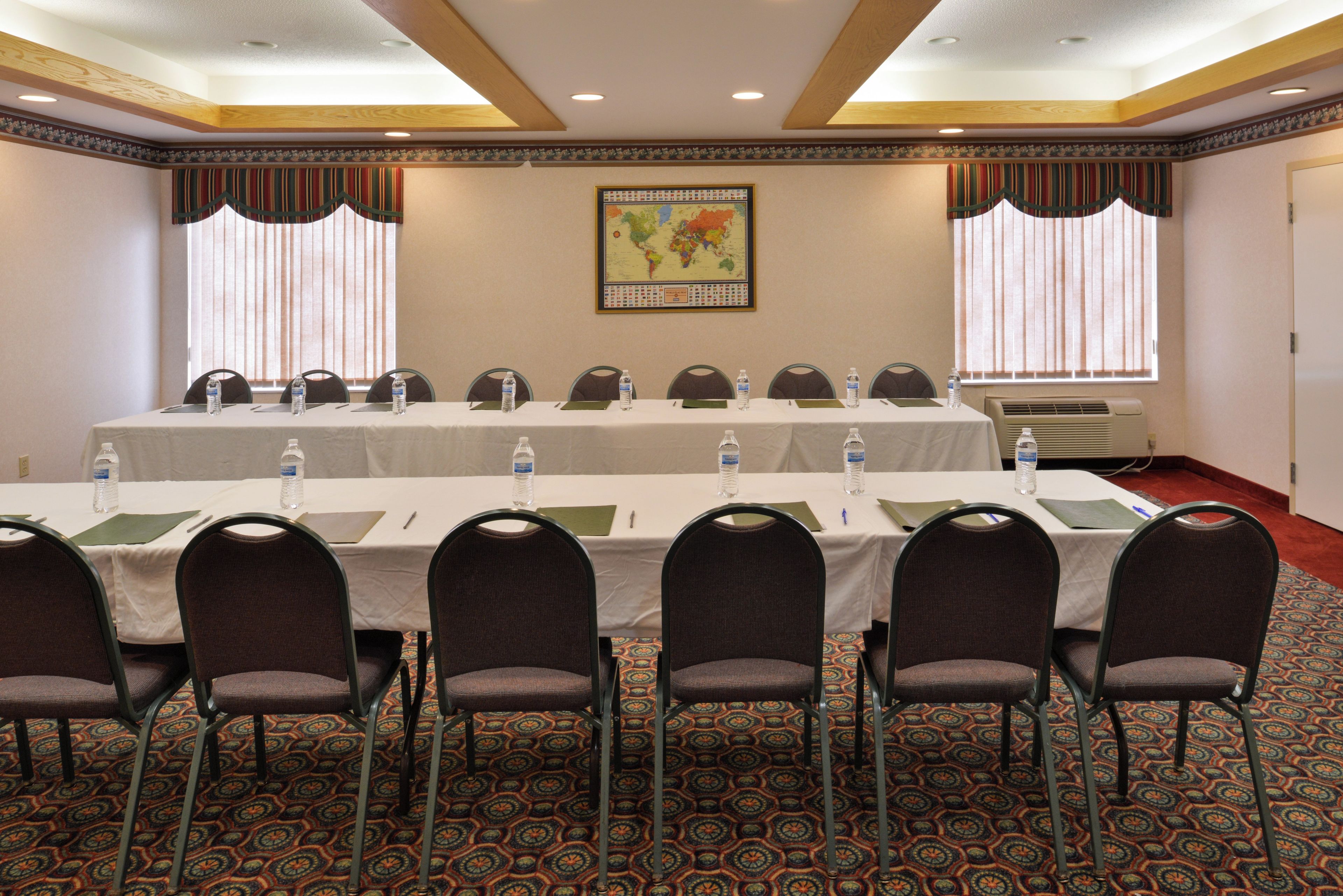 A conference room with a long table, chairs, water bottles, and a world map on the wall.