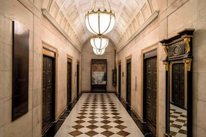 A hallway with a checkered floor, ornate doors, and a large chandelier. - The Ritz-Carlton, Philadelphia (Philadelphia)