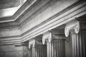 A close-up of classical columns with intricate carvings and a detailed ceiling design.