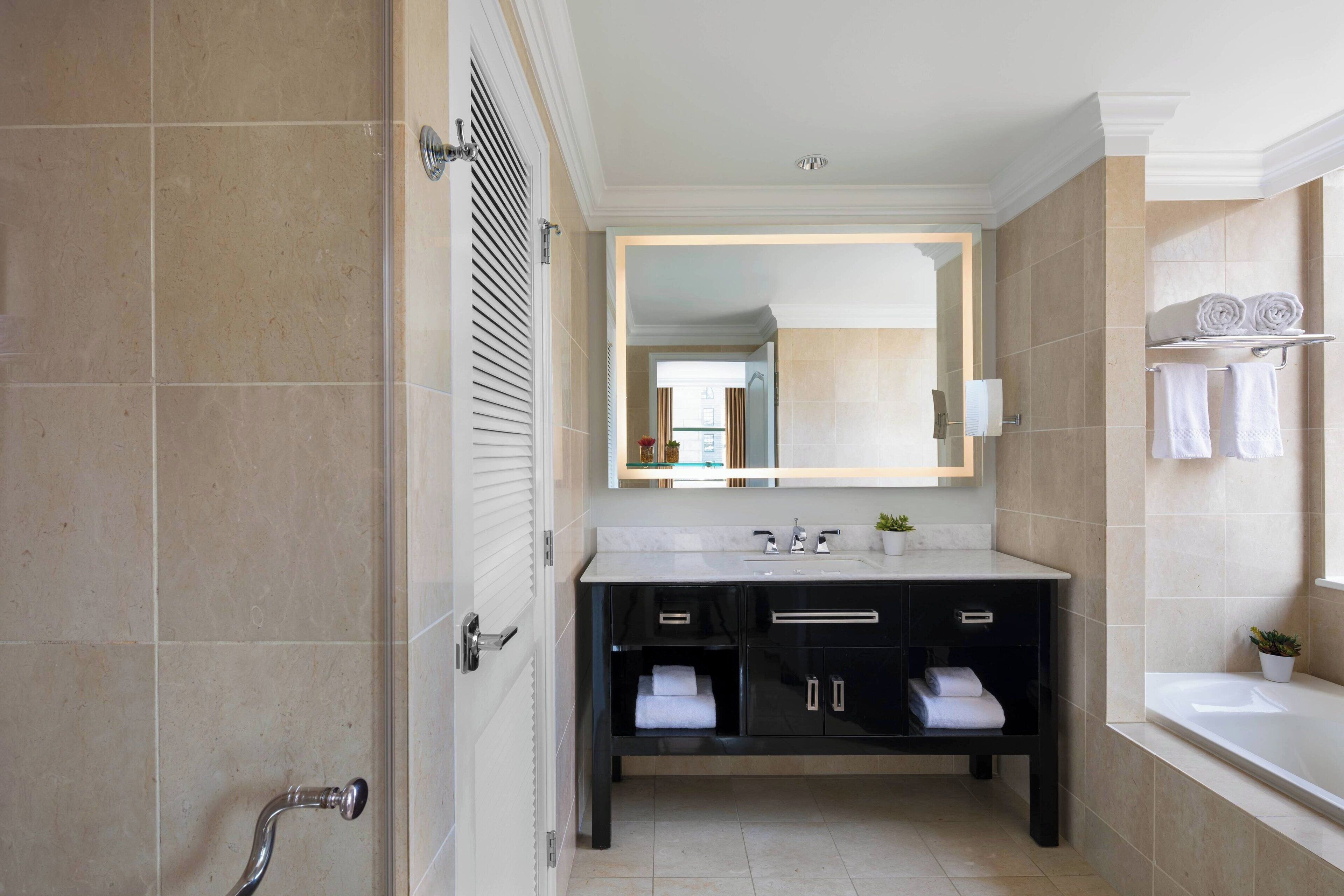 Un baño moderno con un espejo grande, una bañera y una ducha.
