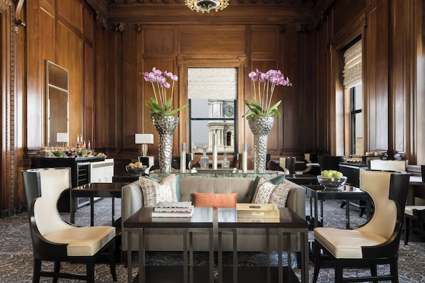 A formal dining room with a high table, multiple chairs, and decorative vases with flowers.