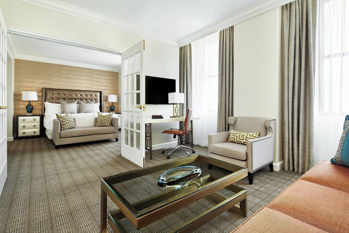 Una habitación de hotel con cama, escritorio, silla, sofá y mesa de centro.