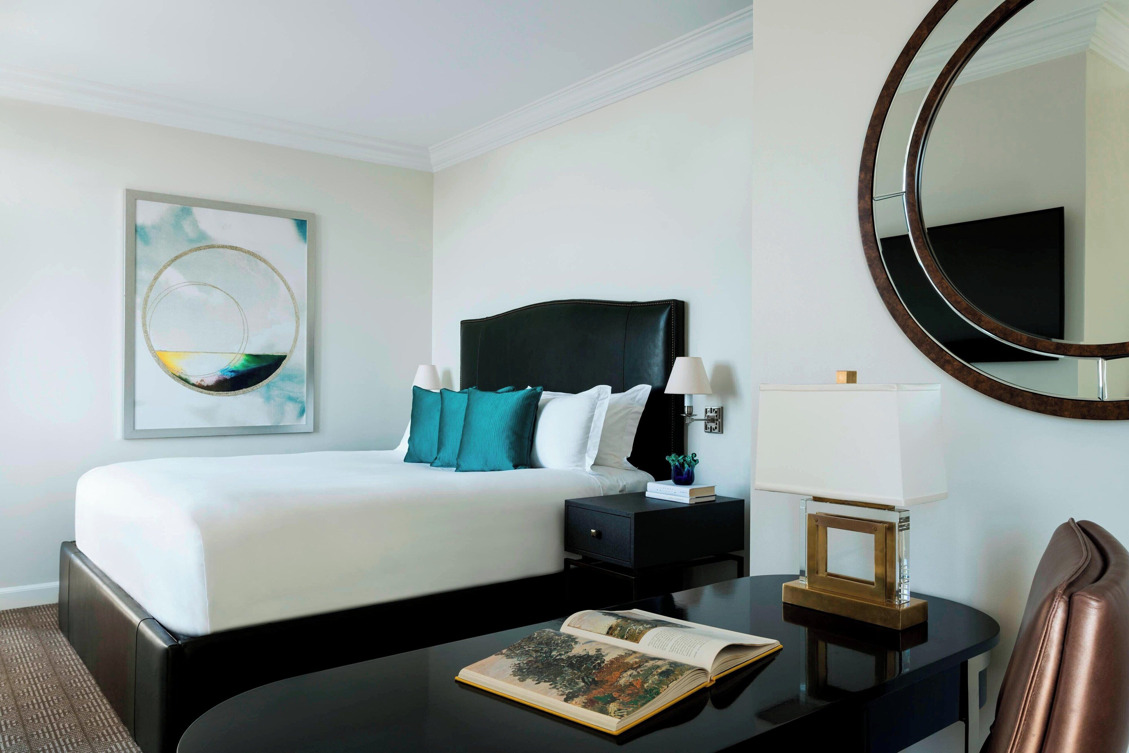 Une chambre d’hôtel avec un lit, une table de chevet, une lampe et un tableau encadré au mur.