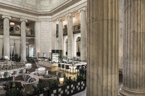 A grand lobby with marble columns, a central bar area, and seating arrangements.