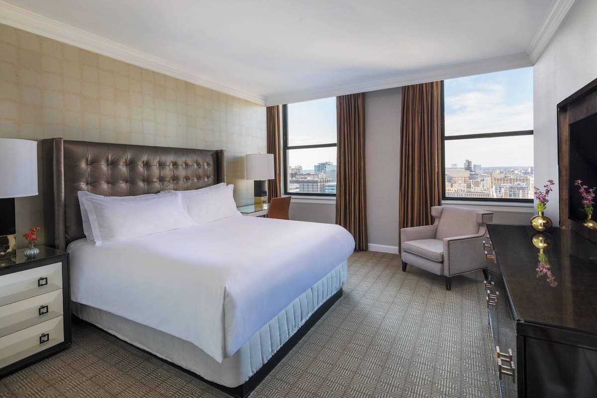 Habitación de hotel con una cama grande, un escritorio, una silla y vistas de la ciudad.