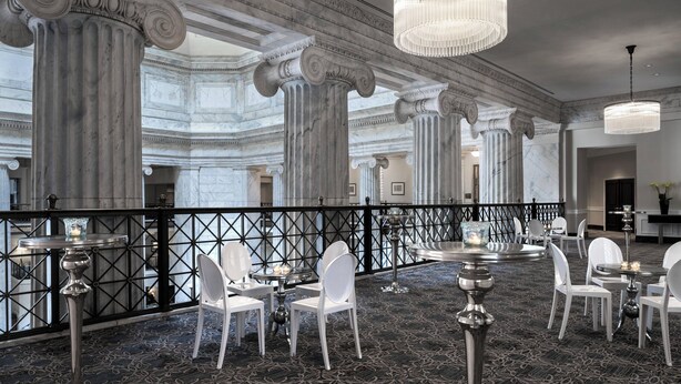 A grand hall with marble columns, chandeliers, and white chairs arranged for dining. - The Ritz-Carlton, Philadelphia (Philadelphia)