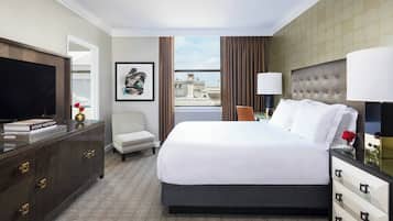 Une chambre d’hôtel avec un grand lit, une télévision, un bureau avec une lampe, une chaise et une vue sur le paysage urbain.