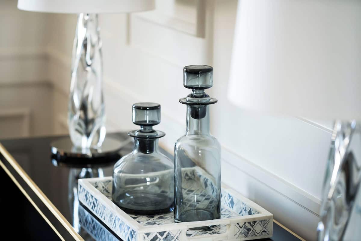 A tray with two glass decanters on a reflective surface.