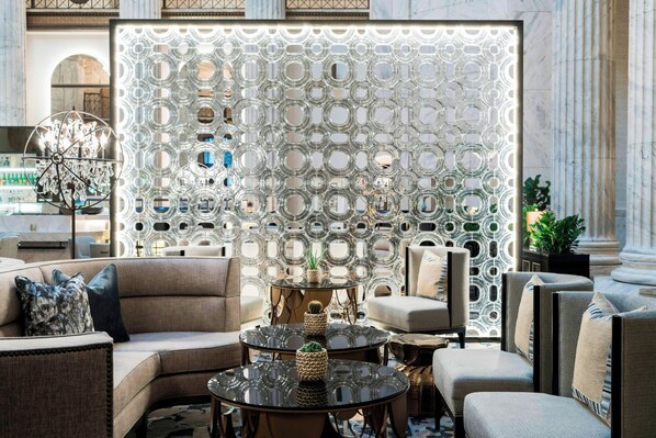 Un moderno vestíbulo con un llamativo muro de cristal, asientos cómodos y un candelabro.