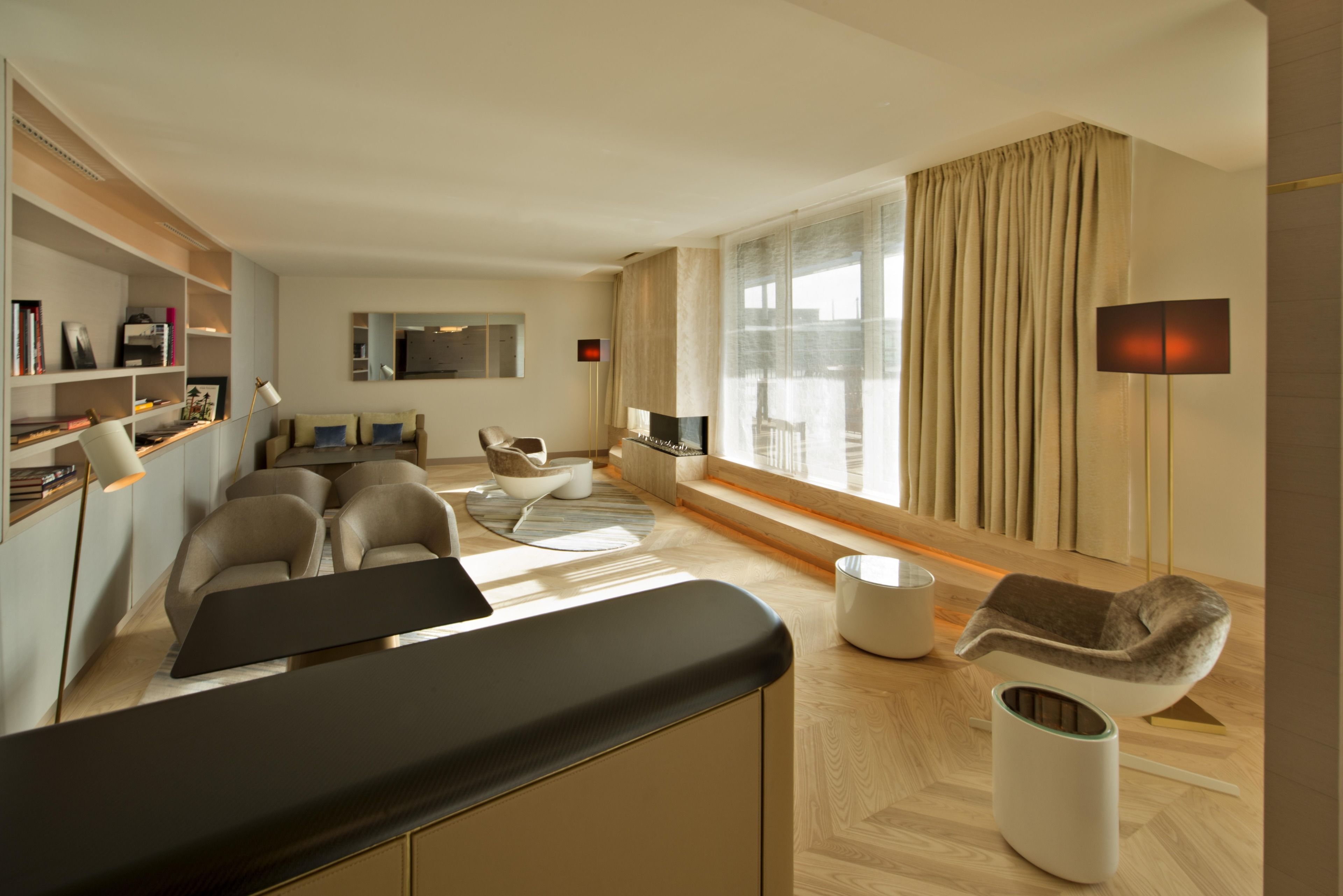 A modern living room with a sofa set, a flat-screen TV, and a large window with curtains.