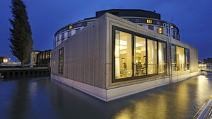 A modern waterfront building with large windows, a wooden facade, and a circular design. - The Ritz-Carlton, Wolfsburg (Wolfsburg)