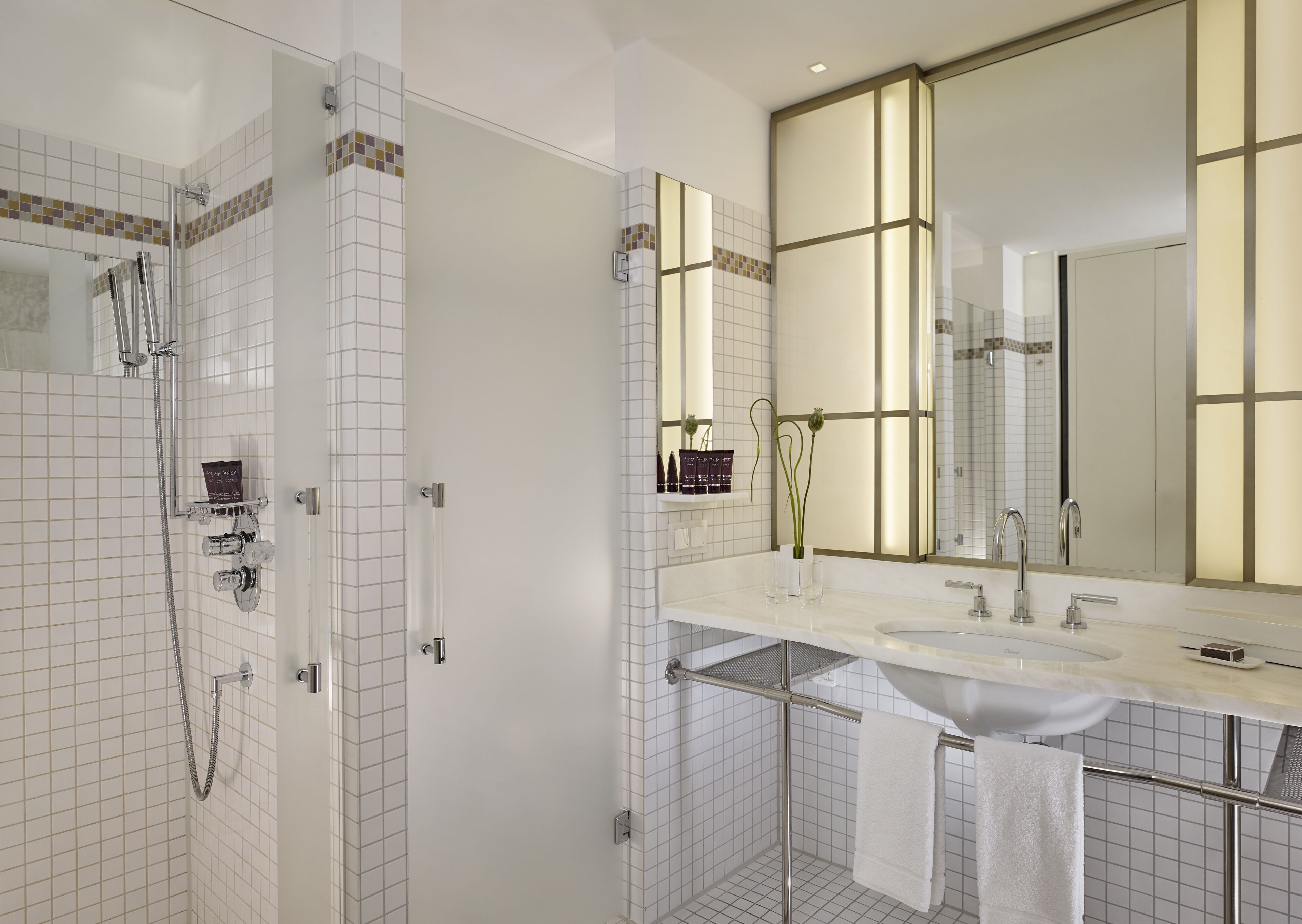 A modern bathroom with a walk-in shower, a large mirror, and a vanity with a sink.