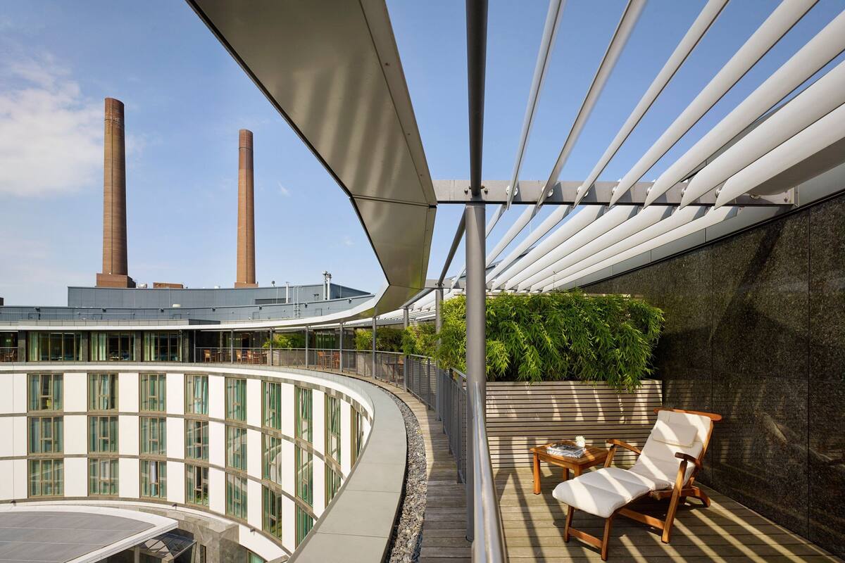 Eine Dachterrasse mit gewölbter Glasscheibe, einem Holzboden und einer Lounge mit Stuhl und Tisch.