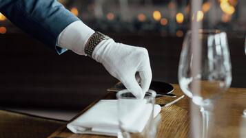 A person setting a table with a white napkin and a wine glass.
