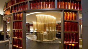 A modern interior with a circular seating area, wooden bookshelves, and a central light fixture. - The Ritz-Carlton, Wolfsburg (Wolfsburg)
