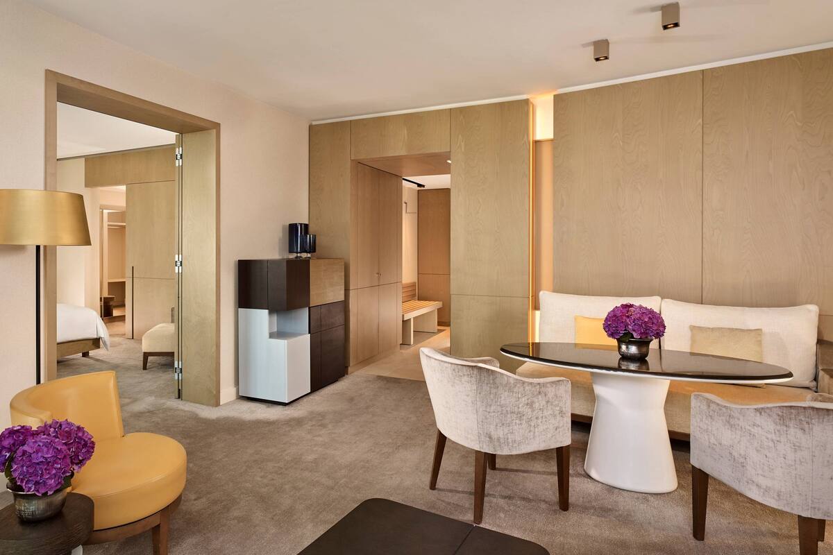 Ein modernes Hotelzimmer mit Essbereich, einer Couch, einem Fernseher und einem Spiegel.
