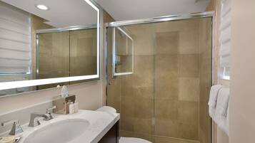 A modern bathroom with a large sink, a toilet, and a glass-enclosed shower.