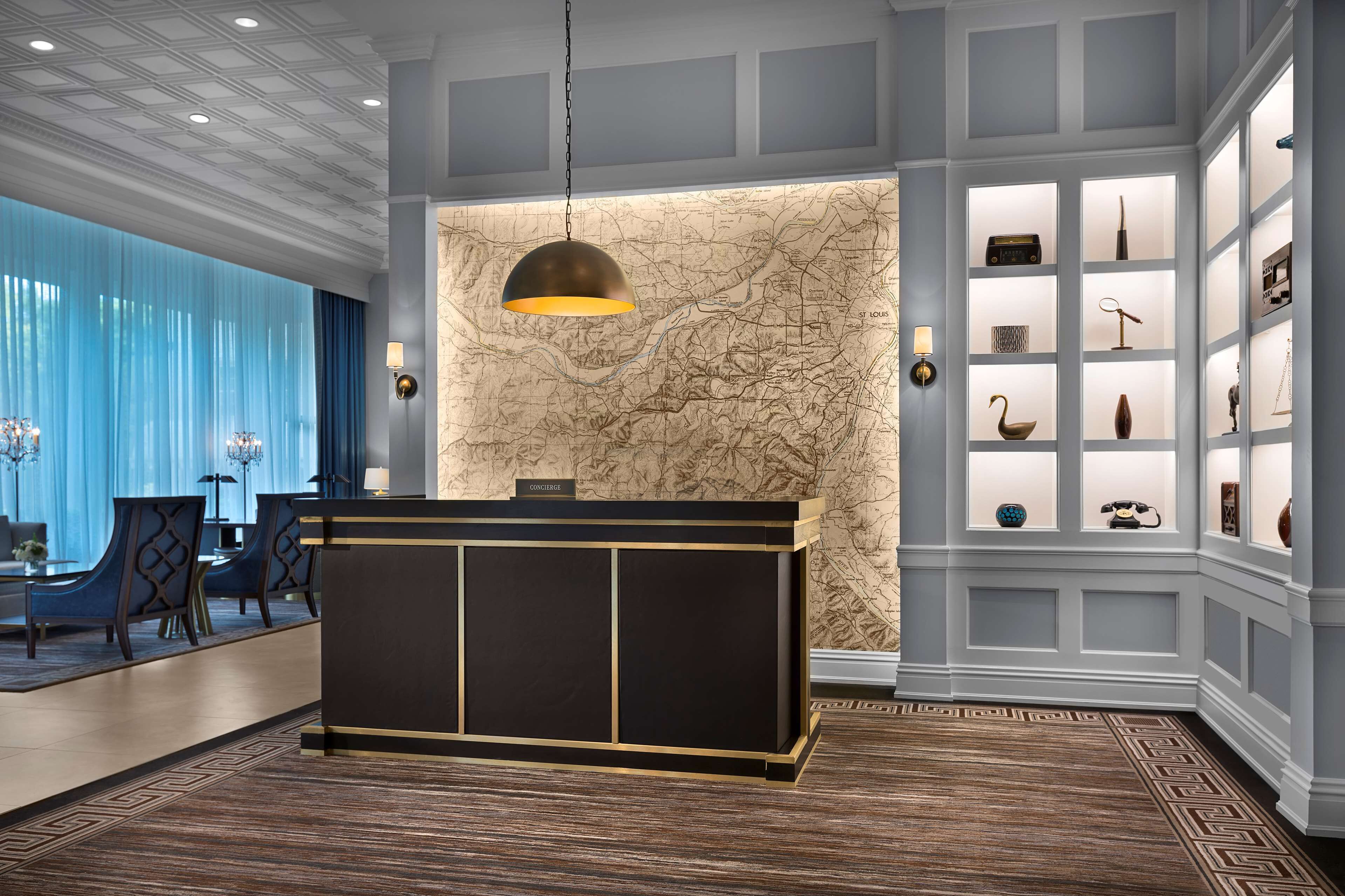 Zona de recepción con escritorio negro y dorado, pared con mapa y cortina azul.