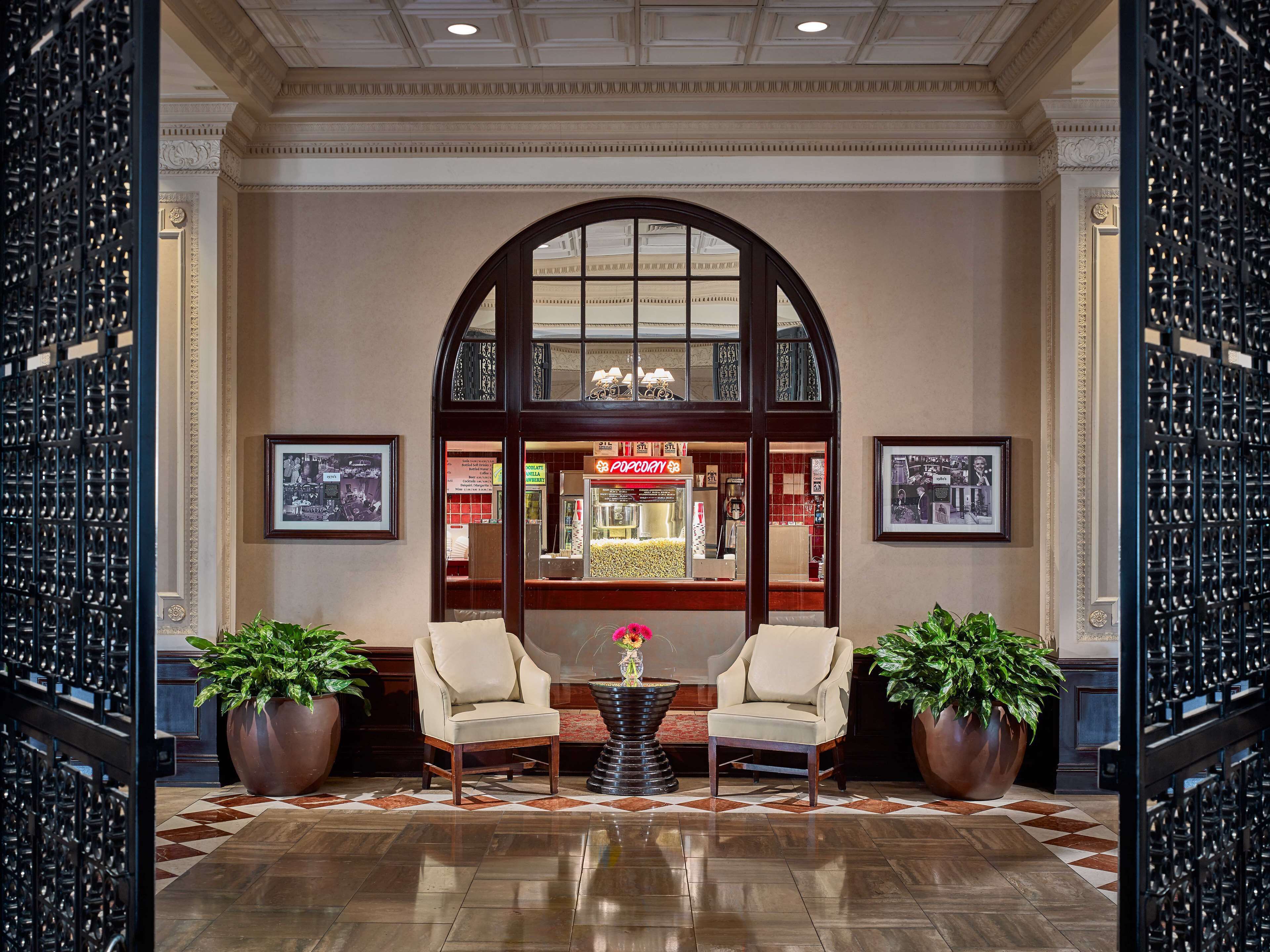 A lobby with two armchairs, a coffee table, and potted plants.