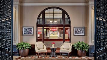 A lobby with two armchairs, a coffee table, and potted plants.