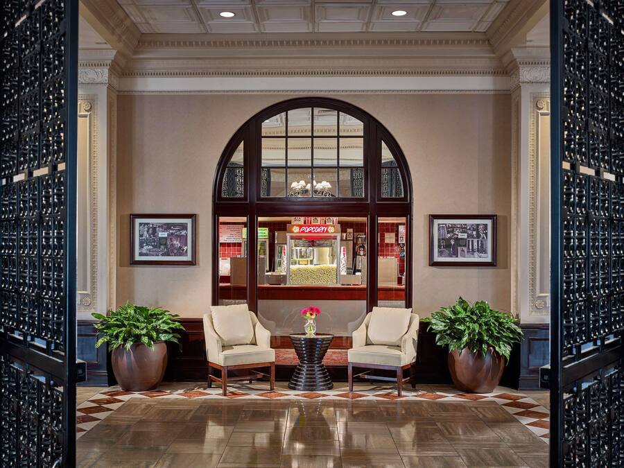 A lobby with two armchairs, a coffee table, and potted plants.