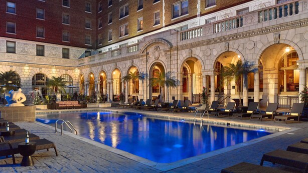 A hotel with a swimming pool, lounge chairs, and a courtyard with palm trees. -  The Royal Sonesta Chase Park Plaza St. Louis (St. Louis)