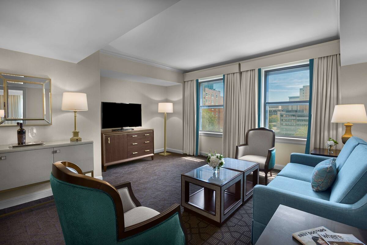 Une chambre d’hôtel équipée d’un téléviseur à écran plat, d’un canapé, d’une table basse et d’une table à manger.