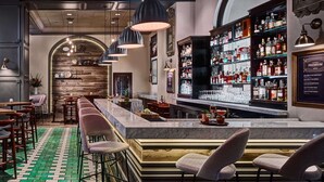 A bar area with a marble counter, bar stools, and a variety of liquor bottles. -  The Royal Sonesta Chase Park Plaza St. Louis (St. Louis)