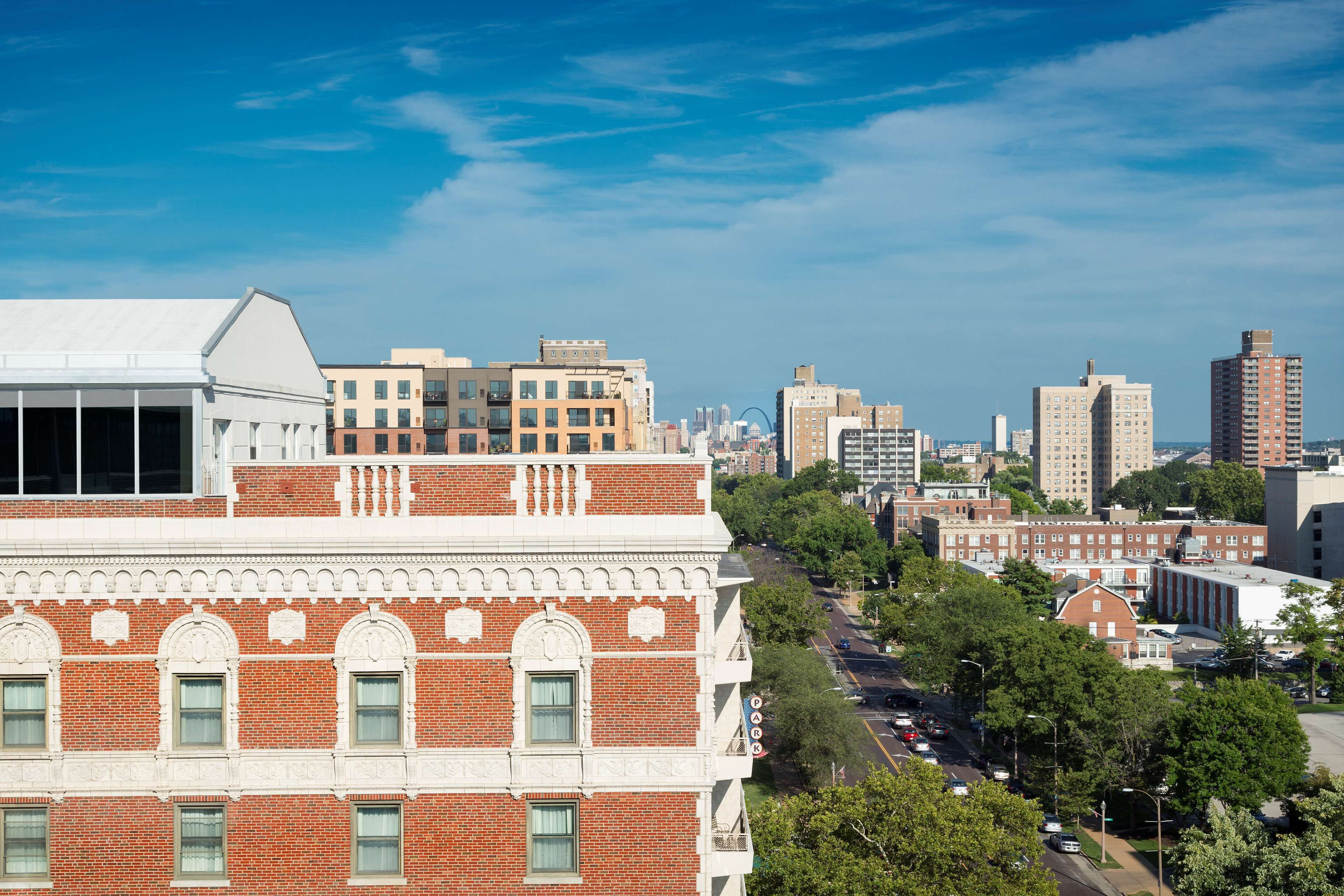 A cityscape with a prominent red brick building featuring arched windows and decorative white trim.