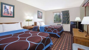 Habitación de hotel con dos camas, un escritorio, un televisor y una ventana con cortinas.