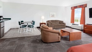 A hotel room with a kitchenette, a sofa, a dining table with chairs, a TV, and a window with curtains. - Super 8 by Wyndham Morden (Morden)