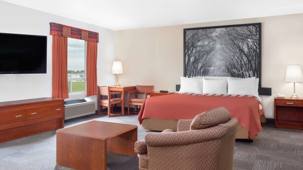 A hotel room with a bed, a desk, a chair, a TV, and a painting on the wall. - Super 8 by Wyndham Morden (Morden)