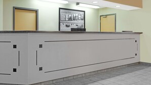 A reception desk with a framed welcome sign, two doors, and a tiled floor. - Super 8 by Wyndham Morden (Morden)