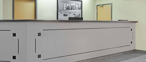 A reception desk with a framed welcome sign, two doors, and a tiled floor.