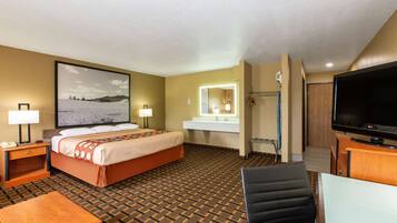 Une chambre d’hôtel équipée d’un lit, d’un bureau, d’une chaise, d’une télévision, d’une salle de bain et d’une grande fenêtre.