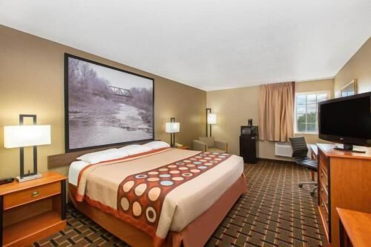 A hotel room with a bed, a desk, a television, and a large window.