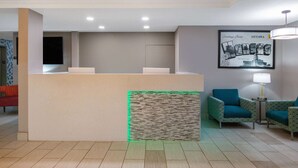 A reception area with a reception desk, two patterned armchairs, a standing lamp, and a framed welcome sign. - Super 8 by Wyndham Ottawa (Ottawa)
