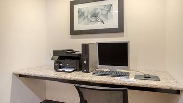 A workspace with a desktop computer, monitor, keyboard, and printer on a granite countertop.