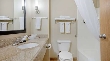 A bathroom with a sink, toilet, and bathtub. There are towels hanging on the wall and a shower curtain.