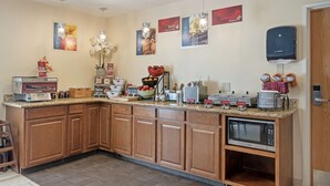 Een keuken met houten kastjes, een magnetron, een koffiezetapparaat en diverse keukenapparaten.