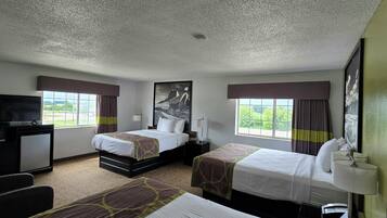 A hotel room with two beds, a desk, a television, and a view of the outdoors.