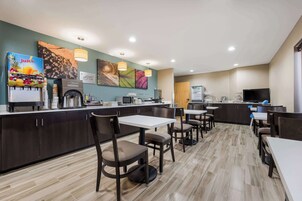 Una cocina de hotel moderna con una barra de zumos, zona de comedor y un televisor de pantalla plana.