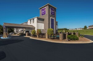 Edificio de Sleep Inn & Suites con diseño moderno, que cuenta con una torre destacada con señalización, un estacionamiento techado y jardines.