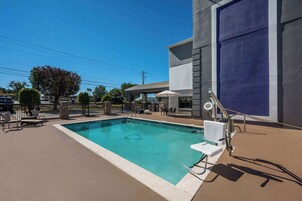 Una piscina con sillas de descanso y un porche cubierto.