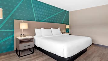 Una habitación de hotel moderna con una cama grande, una mesita de noche con lámpara y una pared con diseño geométrico.