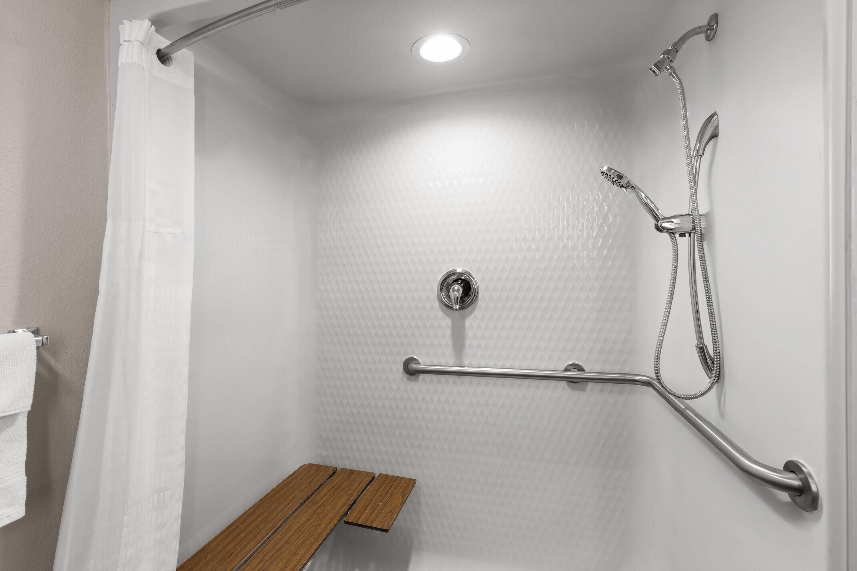 A shower with a handheld showerhead, a handheld showerhead, and a handheld showerhead.