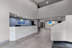 Un área de recepción con mostrador de piedra, un cartel de Days Inn y una escalera.