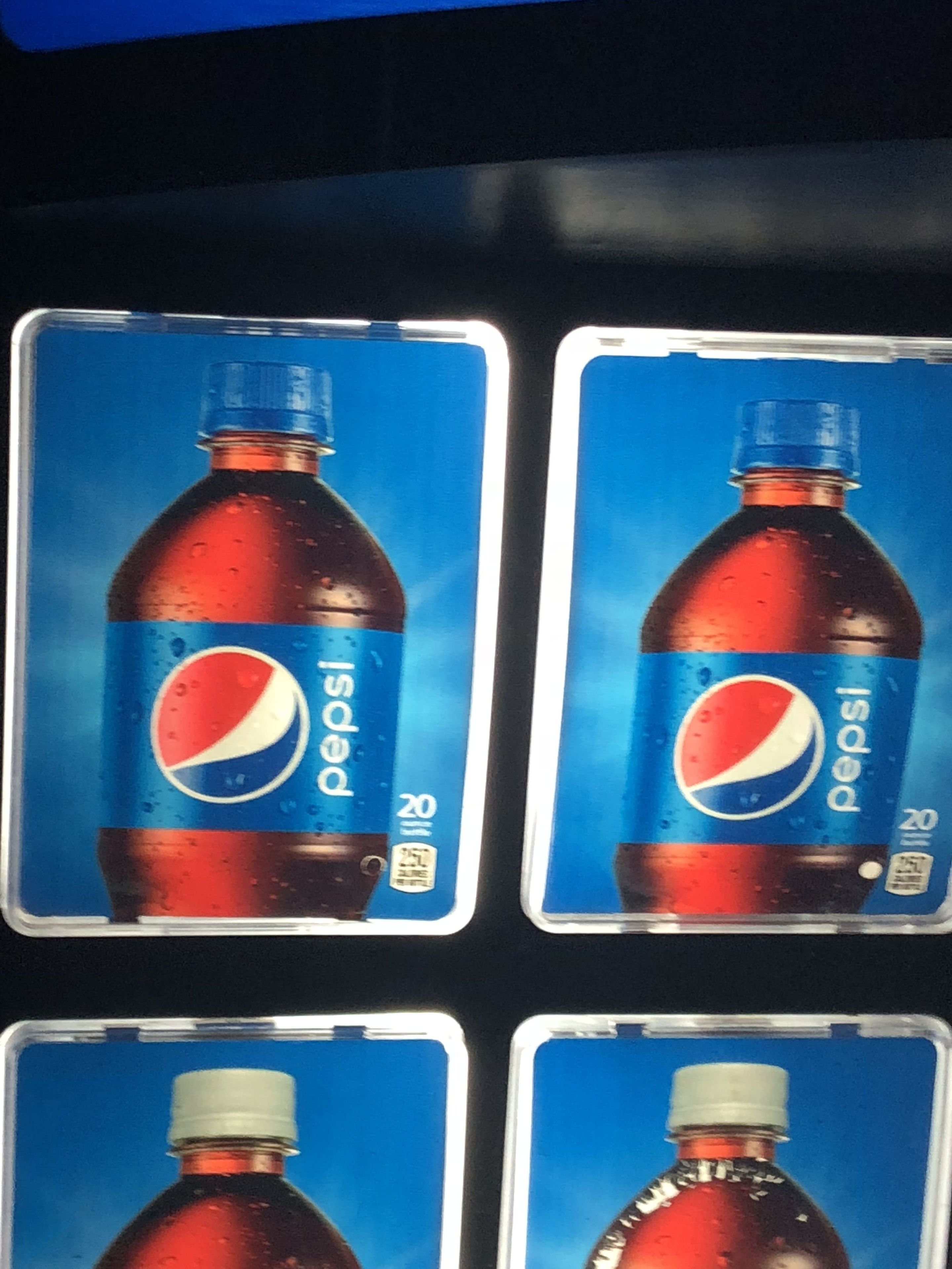 Quatre bouteilles en plastique transparentes de Pepsi dans un distributeur automatique.