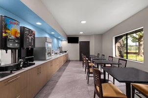 Un área de cocina moderna con dispensador de jugo, una cafetera y un televisor de pantalla plana montado en la pared.